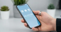 Detail ruky držící smartphone s moderní bankovní aplikací na obrazovce.