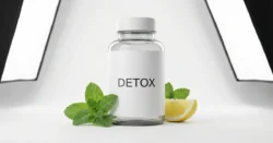 Čistá fotografie generické lahvičky s doplňkem stravy "Detox" s citronem na bílém pozadí.