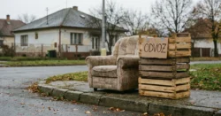 Staré křeslo a dřevěné bedny připravené k odvozu na chodníku před domem.
