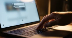 Detail ruky zadávající heslo na klávesnici notebooku s přihlašovací obrazovkou.