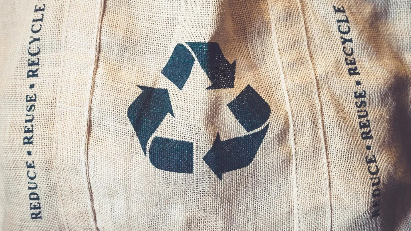 Symbol recyklace na textilii jako připomínka uzavřeného oběhového cyklu